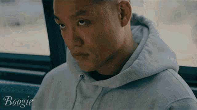 a man wearing a grey hoodie with the word boogie on the bottom right