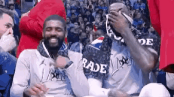 a group of men are sitting in the stands at a basketball game wearing rade jerseys .