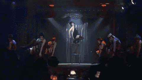 a woman in a black hat is dancing on a stage