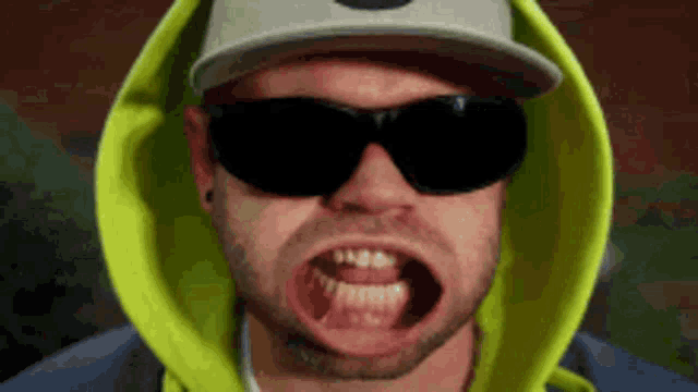 a man wearing sunglasses and a hoodie with his mouth wide open