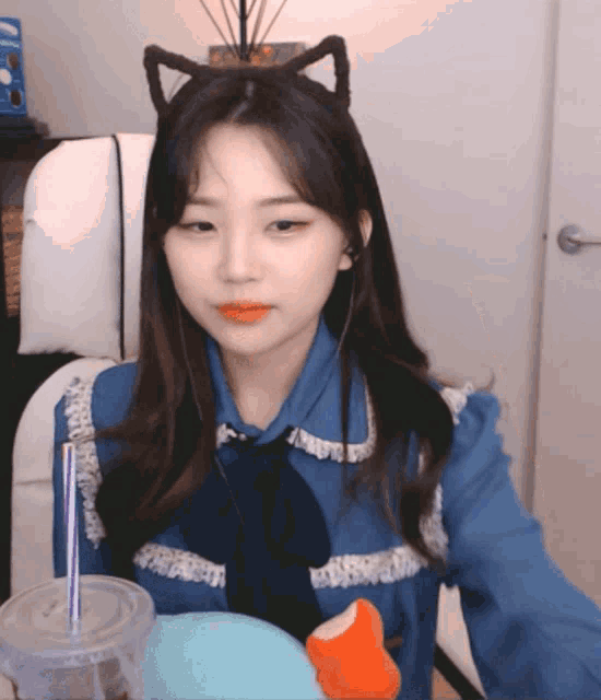 a girl wearing a cat ear headband sits in a chair with a cup of coffee