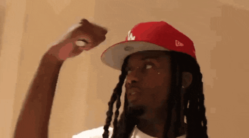 a man with dreadlocks is wearing a red hat with la on it