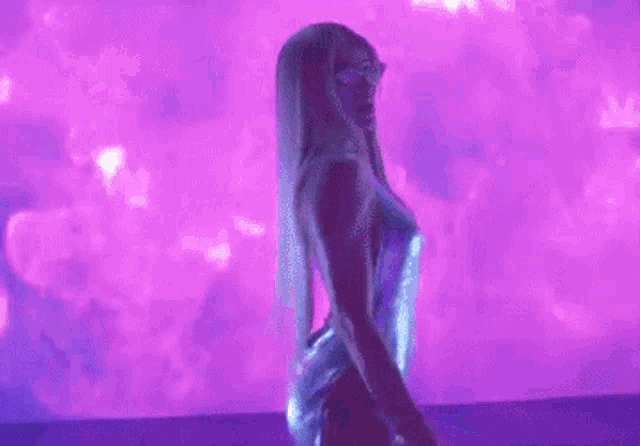 a woman in a blue dress is standing in front of a purple wall .