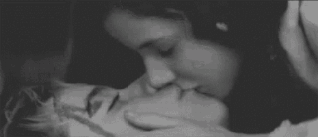 a man and a woman are kissing in a black and white photo .