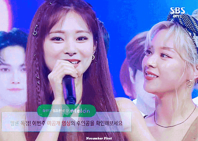 two women are standing next to each other with a sbs logo in the background