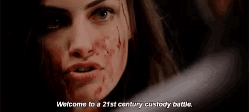a woman with blood on her face is talking to a man in a dark room .