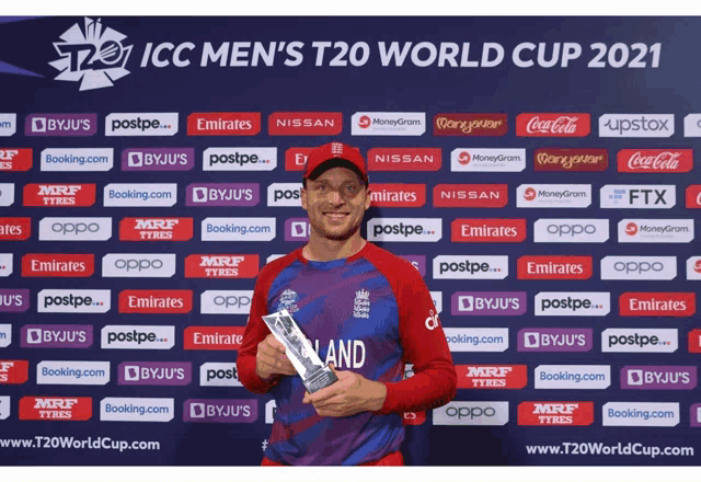 a man holding a trophy in front of a wall that says icc men 's t20 world cup