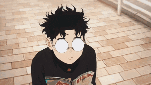 a young boy wearing glasses is reading a book with chinese writing on it
