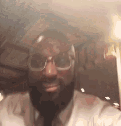 a man with a beard and glasses is taking a picture of himself in a car .
