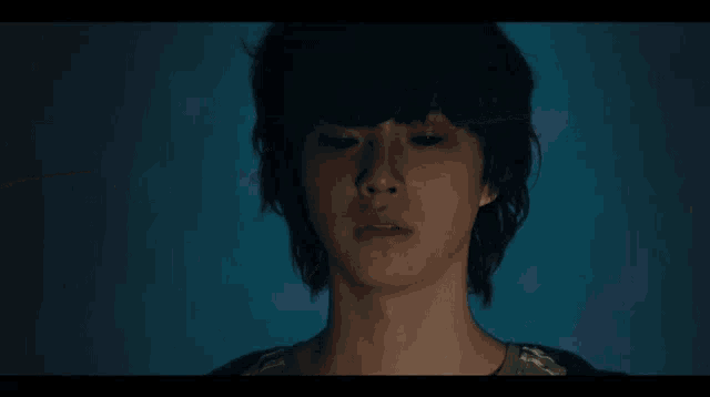 a close up of a person 's face in the dark with a blue background .