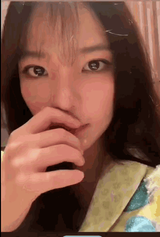 a close up of a woman covering her mouth with her hands
