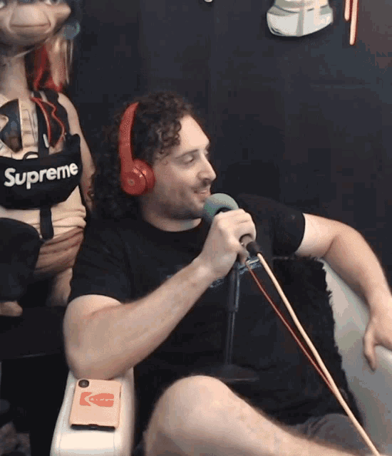 a man wearing headphones and a supreme shirt