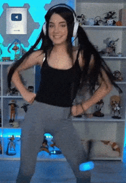 a girl wearing headphones and a black tank top is dancing