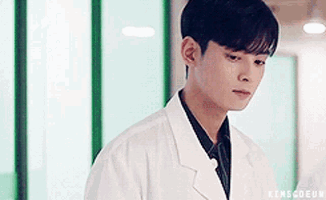 a young man in a lab coat is standing in a room .