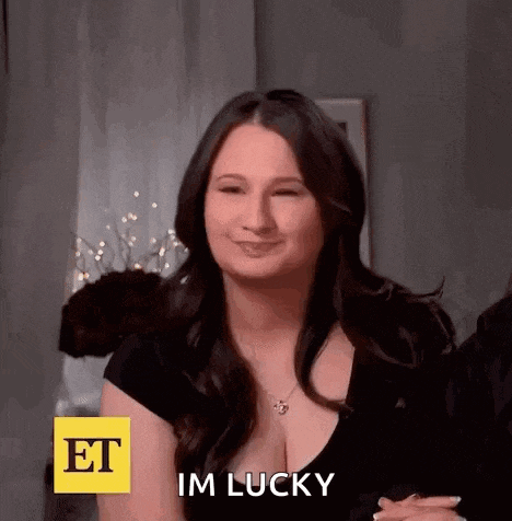 a woman is smiling and saying `` im lucky '' while wearing a black shirt and necklace .