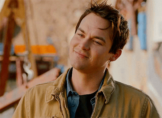 a man wearing a tan jacket is smiling and looking to the side