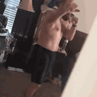 a shirtless man is taking a selfie in a mirror .