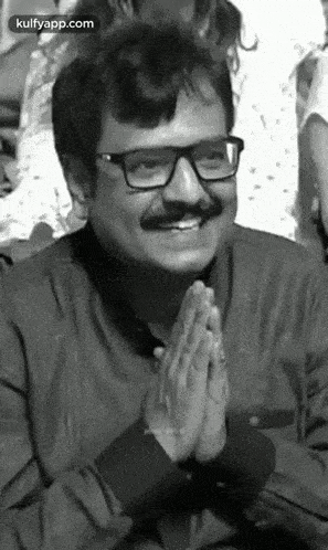 a black and white photo of a man with glasses and a mustache smiling .
