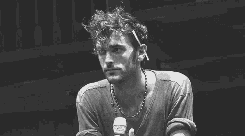 a man is smoking a cigarette while holding a microphone in his hand .