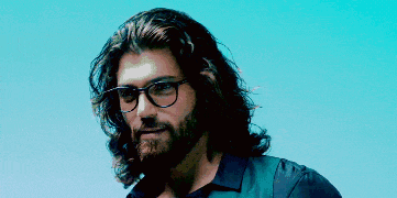 a man with long hair and a beard is wearing glasses .