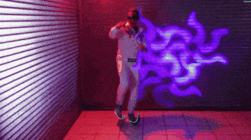 a man is dancing in front of a purple wall with graffiti on it