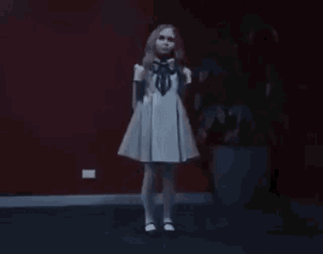 a little girl in a white dress is standing in front of a microphone in a room .