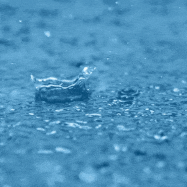 a close up of rain drops falling on a blue surface