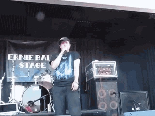 a man singing into a microphone on stage at ernie bal stage