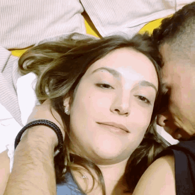 a man kisses a woman on the forehead while laying in bed