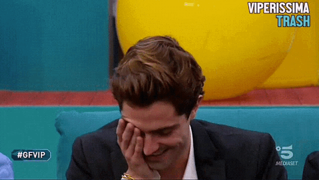 a man in a suit covering his face with his hand while watching a tv show called viperissima trash