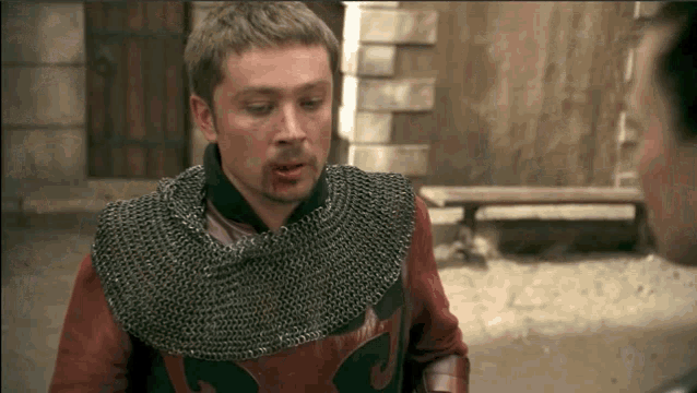 a man wearing chain mail and a red shirt has a bloody mouth