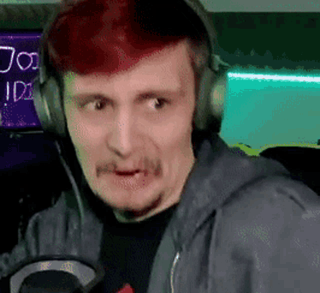 a man wearing headphones and a hoodie is making a funny face .