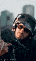 a man wearing headphones and sunglasses is holding a microphone in his hand .