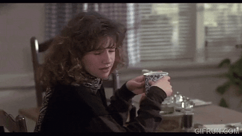a woman is sitting at a table holding a cup of coffee