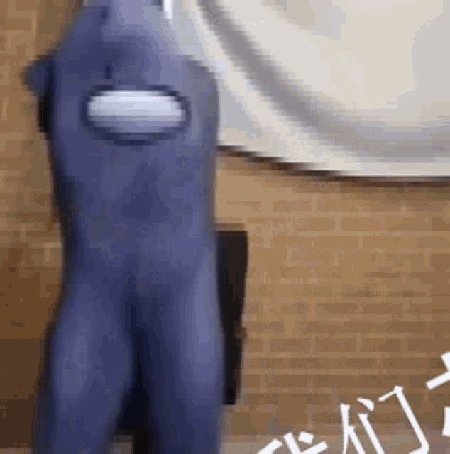 a person in a blue costume is standing in front of a brick wall .