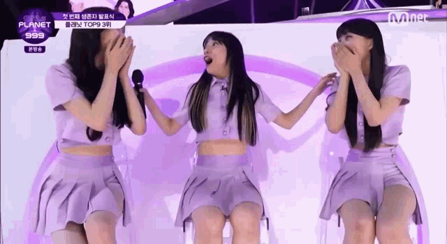 a group of girls are standing next to each other on a stage holding microphones .