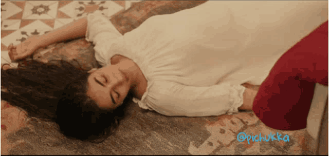 a woman in a white dress is laying on the floor next to a red pillow ..