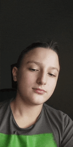 a young boy is wearing a gray shirt with a green stripe on the front .