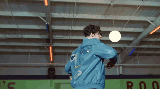 a man wearing a blue jacket with a face on it