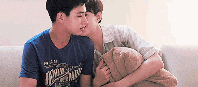 a man wearing a mian shirt kisses another man