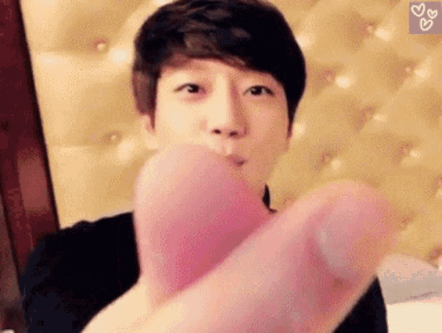 a man is holding a pink heart in his hand and blowing a kiss .