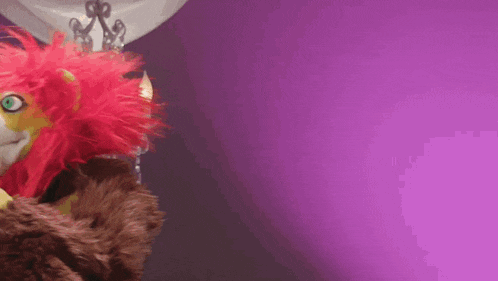 a stuffed animal with red hair and green eyes is standing in front of a purple background