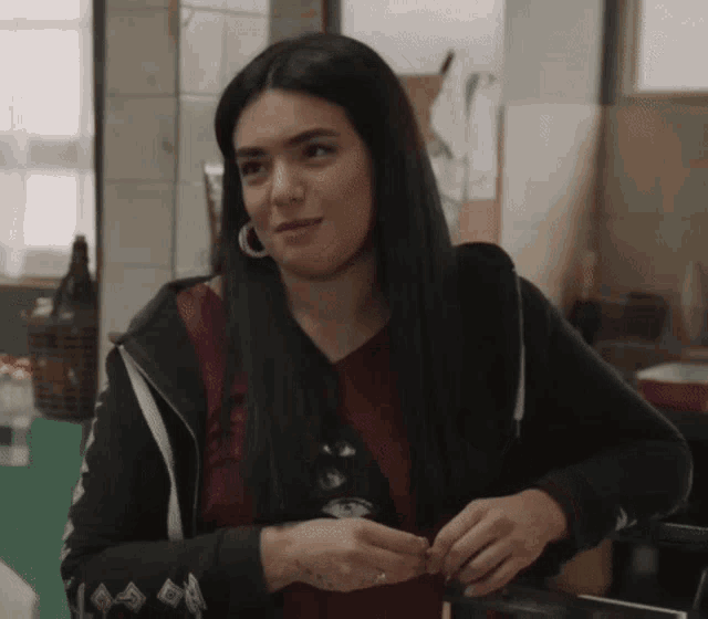 a woman with long black hair is wearing a black hoodie