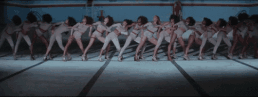 a group of women are dancing in a row in a pool .