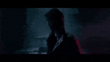a man is standing in a dark room with red lights and chains