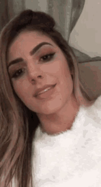 a woman with long hair is wearing a white sweater