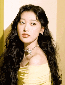 a woman with long black hair is wearing a yellow dress and a pearl necklace