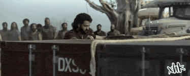 a group of men are standing around a container that says dxs on it
