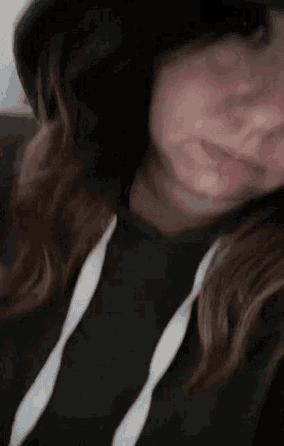 a woman wearing a black hoodie and a black hat is taking a selfie .
