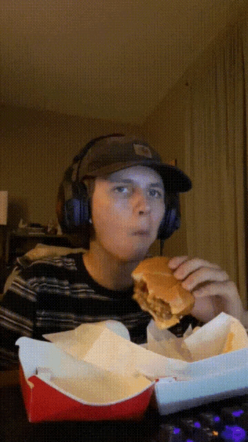a man wearing headphones eating a hamburger